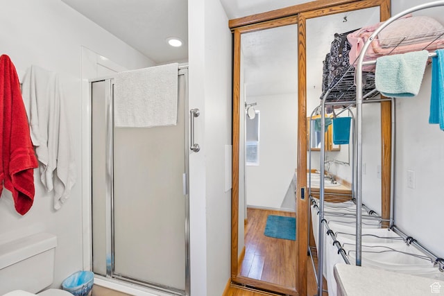 full bath featuring recessed lighting, a stall shower, toilet, and wood finished floors