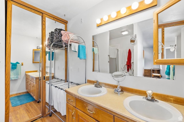 full bathroom featuring a sink, double vanity, and wood finished floors
