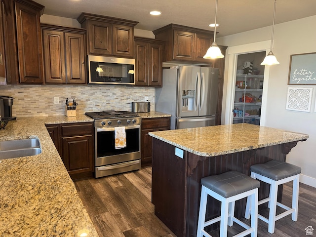 9104 N Cornwall Way E, Eagle Mountain, UT 84005 - kitchen with appliances with stainless steel finishes, dark wood-style flooring, dark brown cabinetry, light stone countertops, and tasteful backsplash