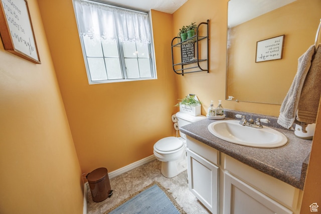 bathroom featuring baseboards, vanity, tile patterned floors, and toilet