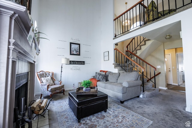 carpeted living room featuring stairway, baseboards, a high ceiling, and a fireplace