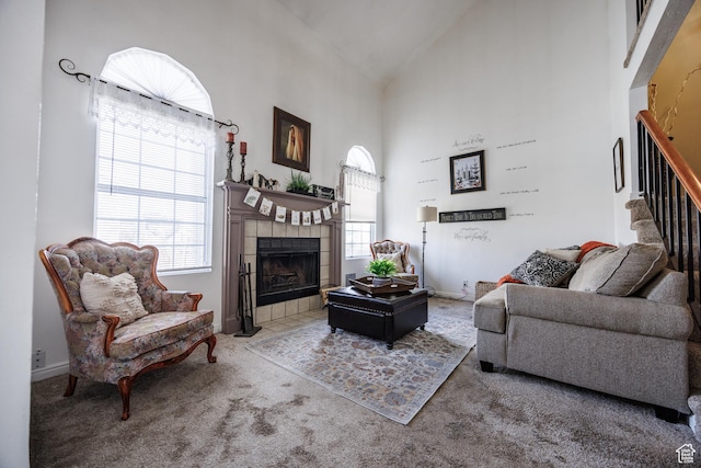 carpeted living room featuring high vaulted ceiling, baseboards, stairway, and a tiled fireplace