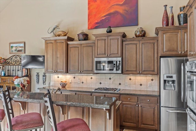6109 S Vine Bend Ln, Murray, UT 84121 - kitchen featuring dark stone countertops, decorative backsplash, appliances with stainless steel finishes, and a kitchen breakfast bar