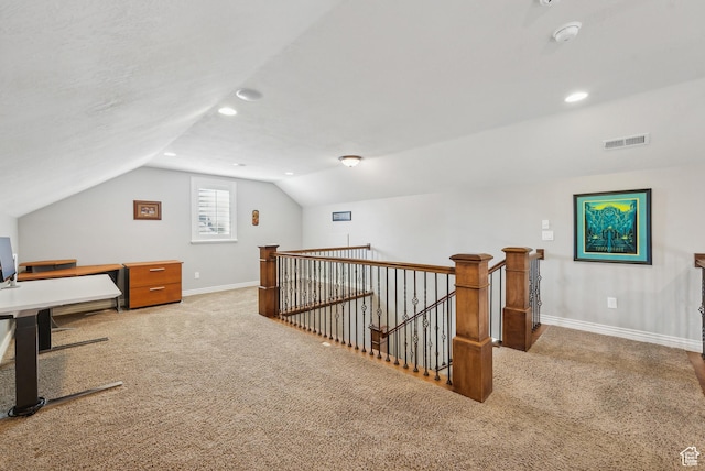 unfurnished office featuring vaulted ceiling, visible vents, carpet flooring, and baseboards