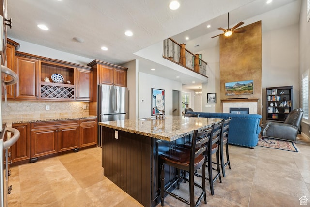 kitchen with light stone counters, open floor plan, freestanding refrigerator, a high ceiling, and recessed lighting