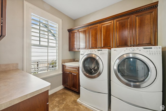 laundry area featuring baseboards, independent washer and dryer, a sink, and cabinet space