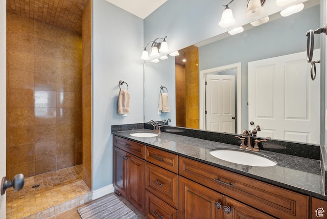 full bathroom featuring a sink, double vanity, and tiled shower