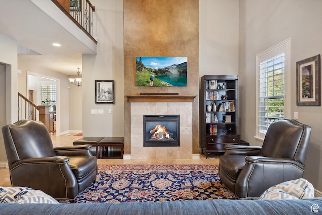 living room featuring baseboards, a towering ceiling, a fireplace, and an inviting chandelier