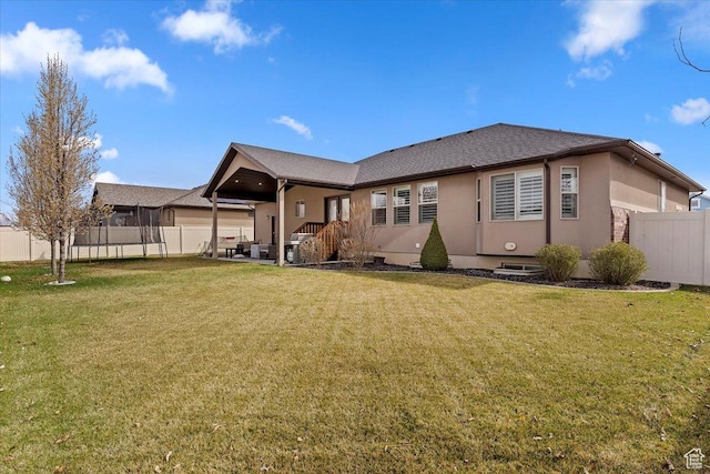 back of property featuring fence, a lawn, and stucco siding