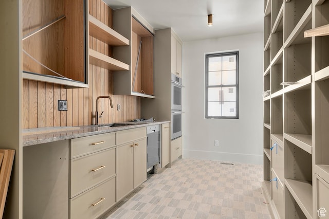 kitchen with open shelves, a sink, double wall oven, dishwasher, and baseboards