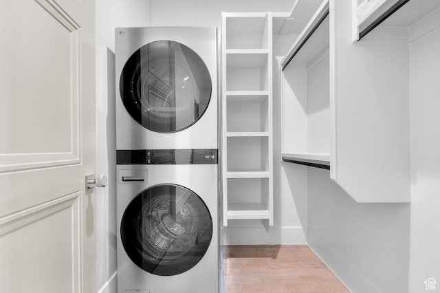 laundry room with wood finished floors, stacked washing maching and dryer, and laundry area