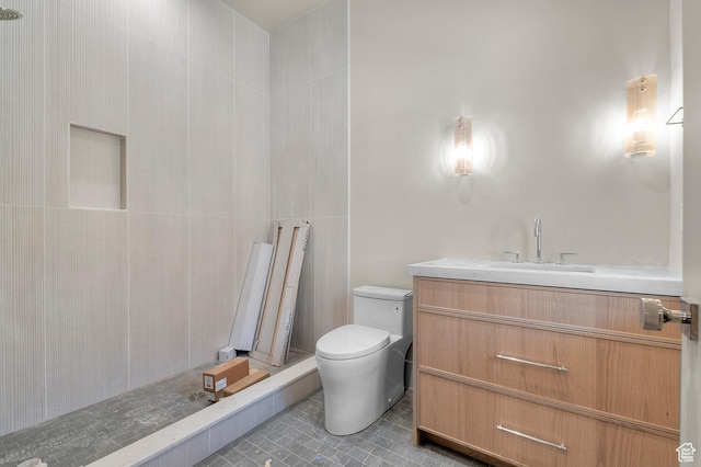 full bath featuring a tile shower, tile patterned flooring, vanity, and toilet