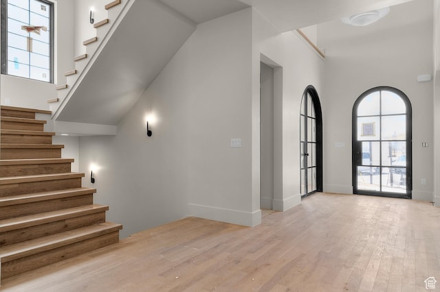 interior space with wood finished floors, a wealth of natural light, baseboards, and a high ceiling
