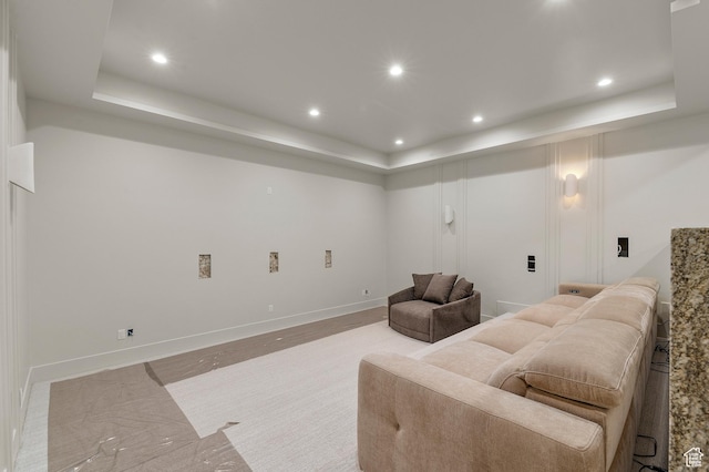 living room featuring recessed lighting, a raised ceiling, and baseboards