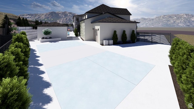 view of side of home with fence, stucco siding, and a mountain view