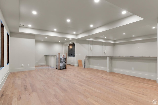 basement featuring light wood-type flooring, baseboards, arched walkways, and recessed lighting