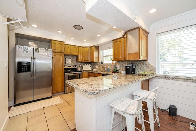 2005 N 500 E, North Ogden, UT 84414 - kitchen featuring brown cabinets, decorative backsplash, stainless steel appliances, a peninsula, and light stone countertops