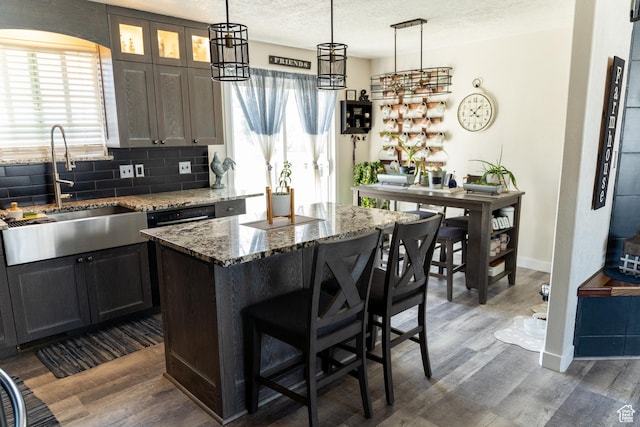 kitchen with a kitchen breakfast bar, a healthy amount of sunlight, a sink, dark wood-type flooring, and baseboards