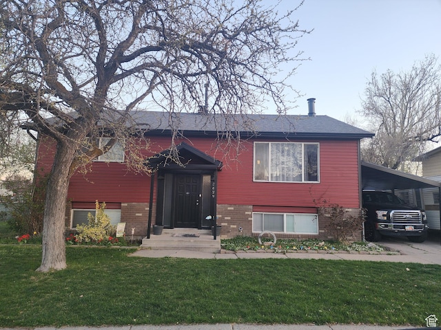split foyer home featuring brick siding, an attached carport, and a front yard