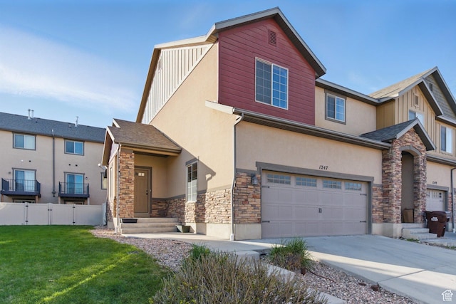 view of front of house with stone siding, concrete driveway, fence, a front yard, and stucco siding