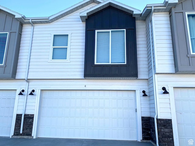 150 W Seasons Ln Unit 4, Garden City, UT 84028 - view of home's exterior with board and batten siding, an attached garage, and stone siding
