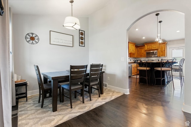 dining area with baseboards, dark wood-style floors, arched walkways, and recessed lighting
