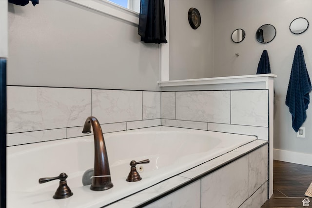 full bathroom featuring a bath, wood finished floors, and baseboards