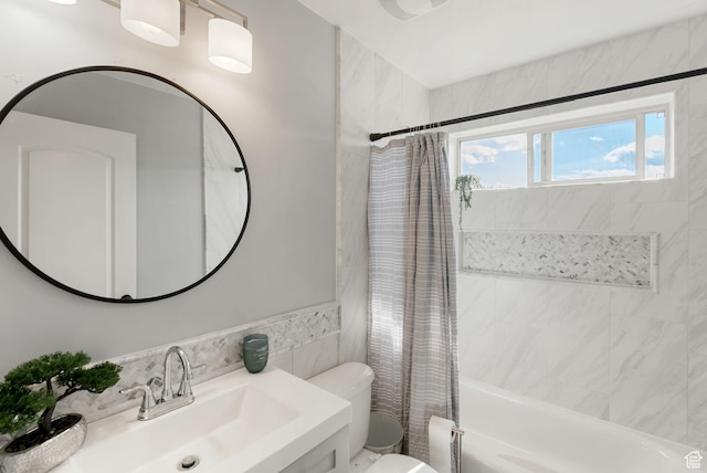 bathroom with shower / tub combo, toilet, vanity, and tile walls