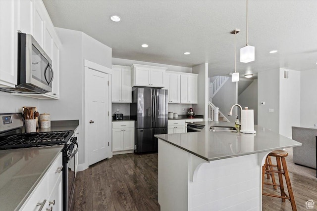 4941 W Chrome Rd, Herriman, UT 84096 - kitchen featuring white cabinets, dark wood-style floors, a breakfast bar, a sink, and appliances with stainless steel finishes