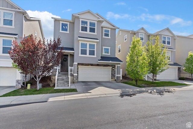 townhome / multi-family property featuring an attached garage, stone siding, and concrete driveway