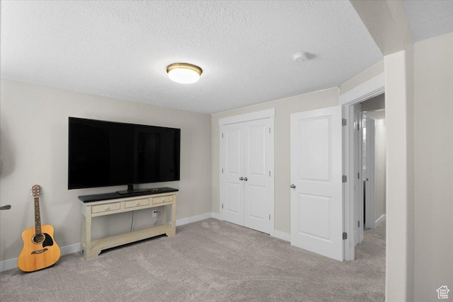 unfurnished bedroom featuring baseboards, carpet floors, a textured ceiling, and a closet