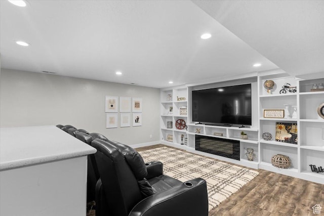 living area with built in shelves, wood finished floors, and recessed lighting