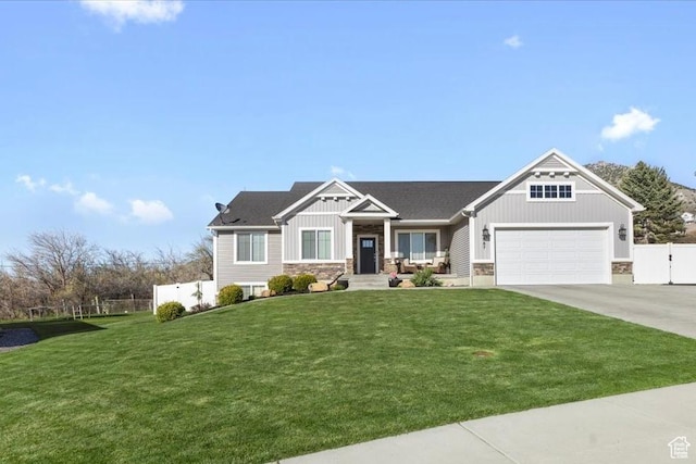 craftsman-style home with fence, a front lawn, an attached garage, board and batten siding, and driveway