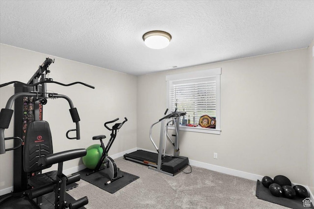 exercise room featuring a textured ceiling, carpet flooring, and baseboards