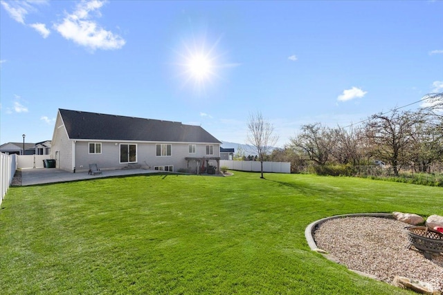 rear view of house featuring a lawn, a fenced backyard, a fire pit, and a patio