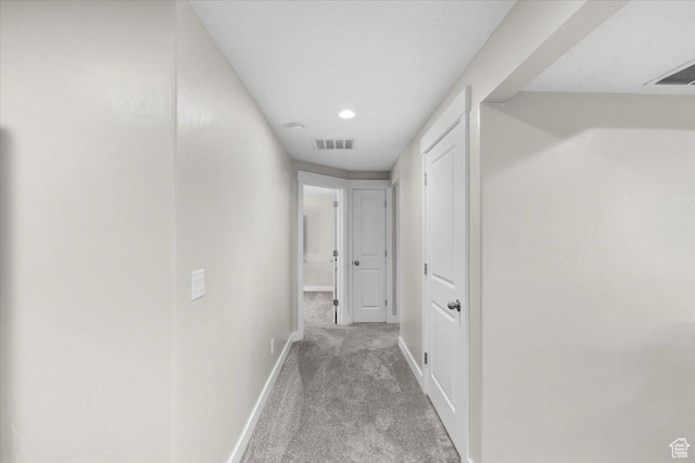hallway with baseboards, carpet flooring, and visible vents