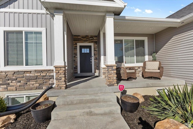 property entrance with board and batten siding, covered porch, and stone siding
