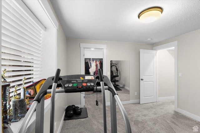 workout room with carpet floors, a textured ceiling, and baseboards