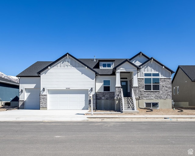 craftsman-style home with concrete driveway, an attached garage, stone siding, and board and batten siding