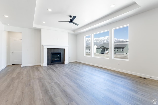 3080 N 2875 W Unit 25, Plain City, UT 84404 - unfurnished living room featuring visible vents, a tray ceiling, light wood-type flooring, and ceiling fan