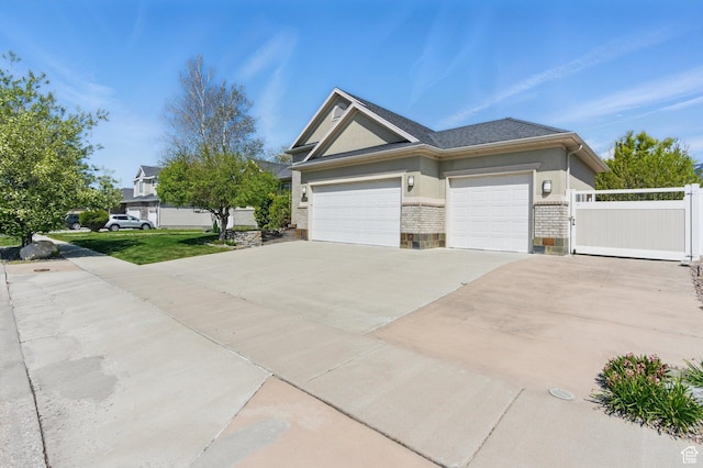 view of front of house featuring a gate, concrete driveway, an attached garage, fence, and stucco siding