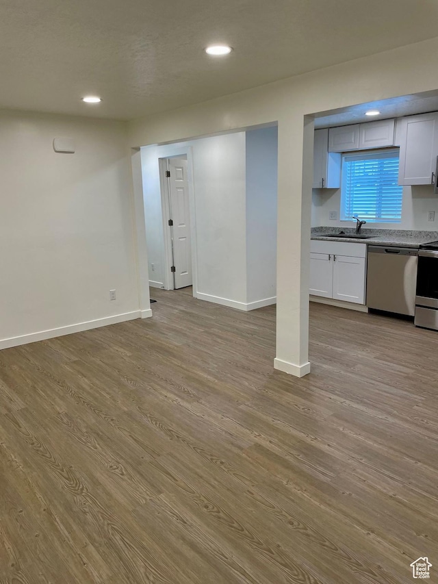 below grade area featuring wood finished floors, baseboards, recessed lighting, and a sink