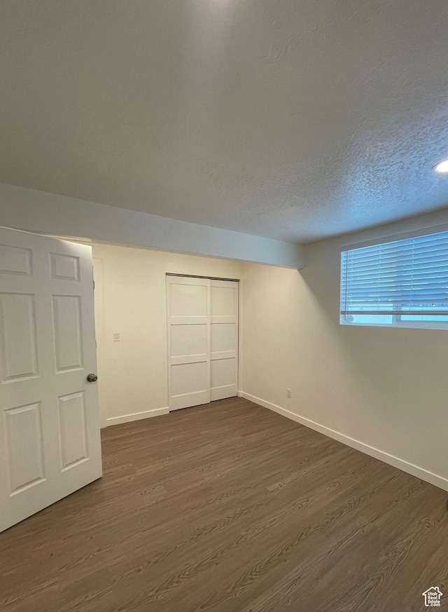 unfurnished bedroom with dark wood-style floors, baseboards, a closet, and a textured ceiling