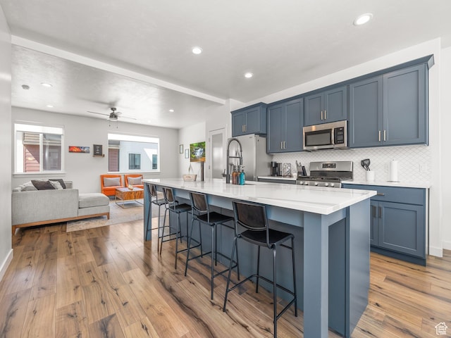 452 S Wood Stream Rd, American Fork, UT 84003 - kitchen with stainless steel appliances, a spacious island, light wood-type flooring, tasteful backsplash, and a breakfast bar area