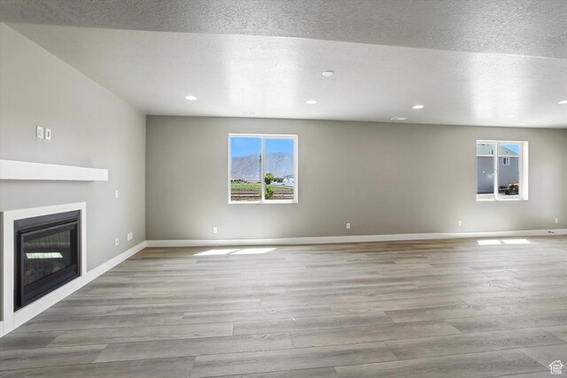 1273 S 240 W Lot 9, Tremonton, UT 84337 - unfurnished living room with a glass covered fireplace, wood finished floors, recessed lighting, and a textured ceiling
