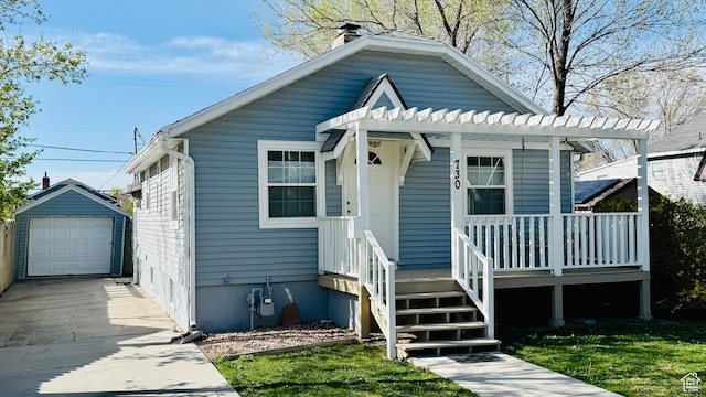 bungalow-style house featuring a detached garage, driveway, a chimney, and an outbuilding