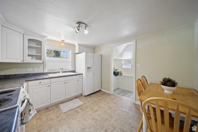 730 E 3155 S, Millcreek, UT 84106 - kitchen with dark countertops, electric stove, a sink, white refrigerator with ice dispenser, and white cabinets