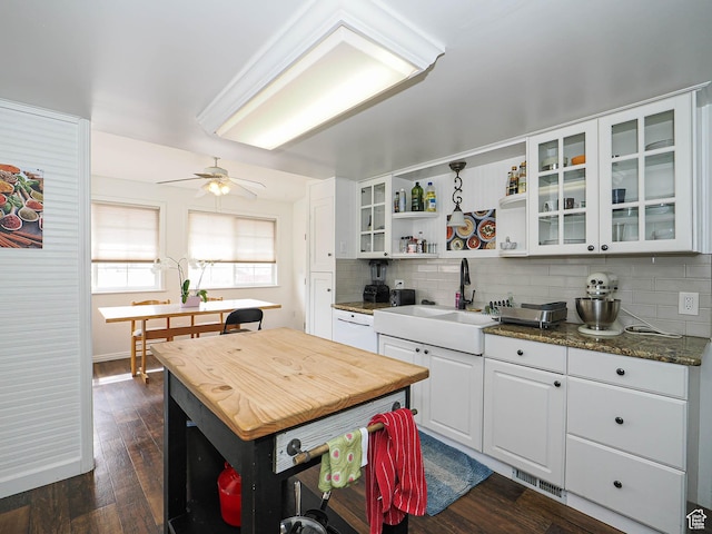 kitchen with a sink, backsplash, white cabinetry, open shelves, and dark wood-type flooring
