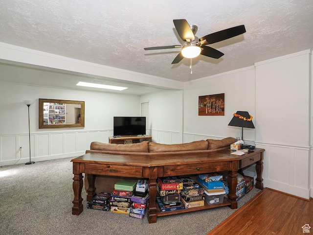 living room featuring a textured ceiling, a decorative wall, and ceiling fan
