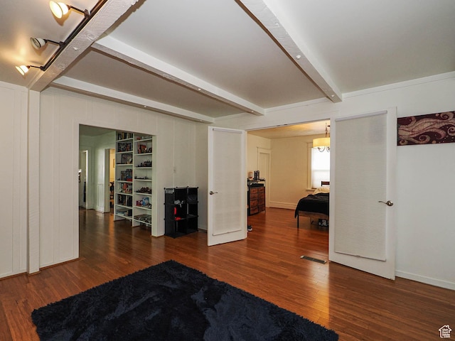 interior space with baseboards, visible vents, wood finished floors, and beamed ceiling
